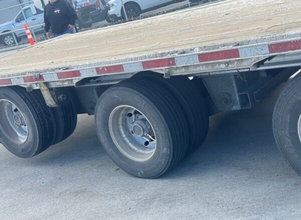 Rear axle wheels and tires beneath the aluminum deck of the 2023 Extreme three-axle step deck trailer