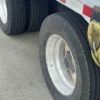Close-up of a 17.5-inch trailer tire, wheel hub and tire inflation hoses on the 2023 Extreme step deck
