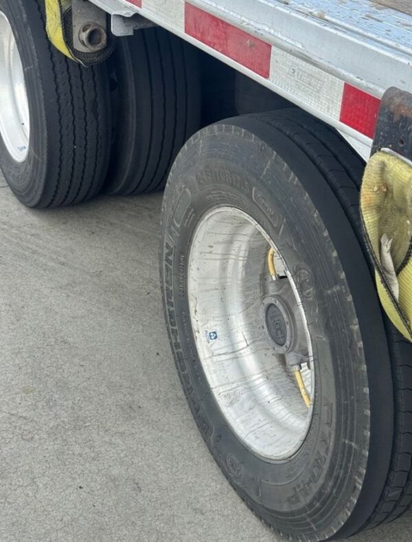 Close-up of a 17.5-inch trailer tire, wheel hub and tire inflation hoses on the 2023 Extreme step deck