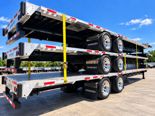 Rear three-quarter view of three stacked Wabash Combo step deck trailers showing aluminum decks, wheels and side rails