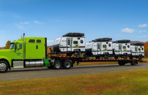 The picture shows a step deck trailer loaded with camper trailers.